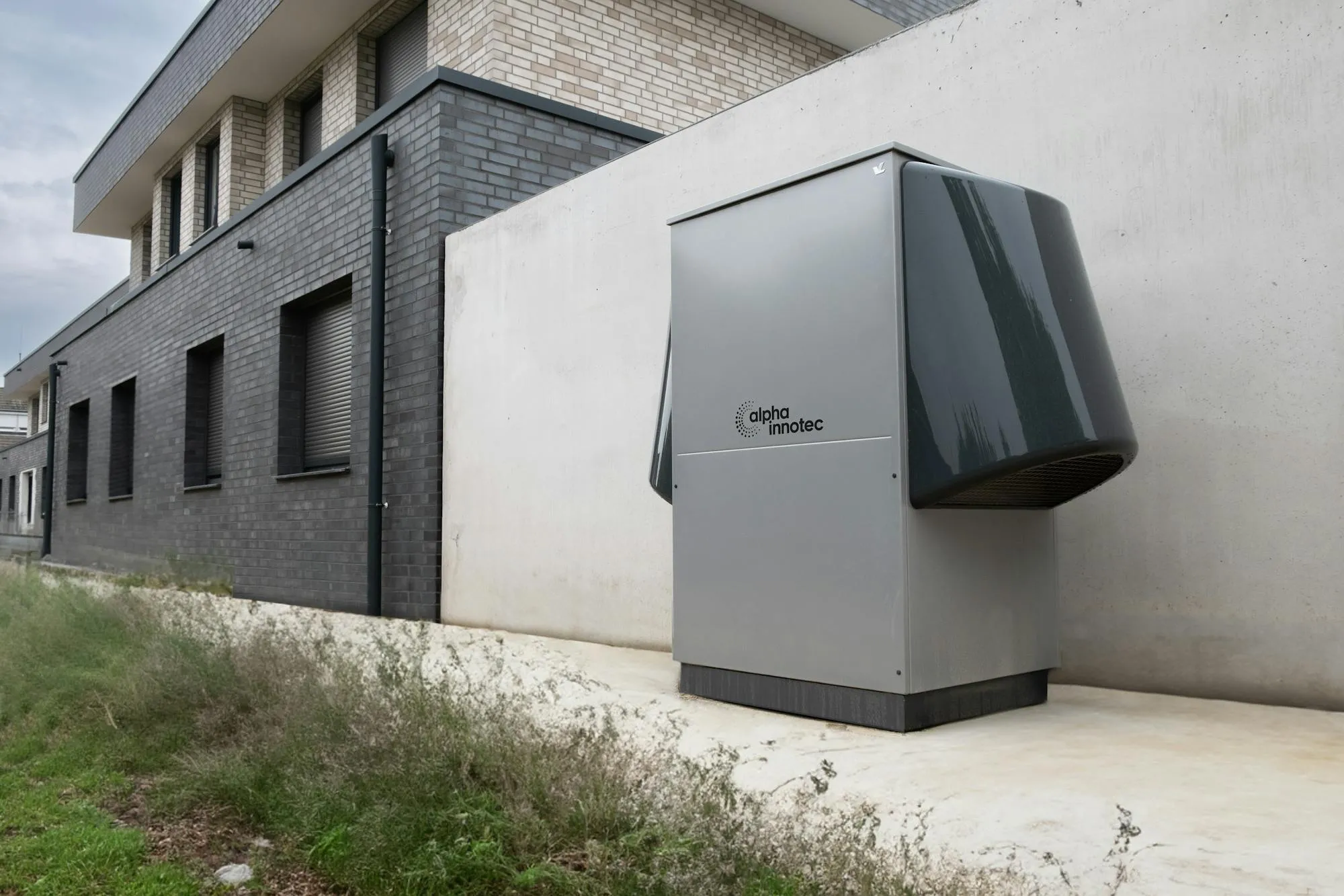 Jednostka zewnętrzna pompy ciepła powietrze-woda zainstalowana przy ścianie domu